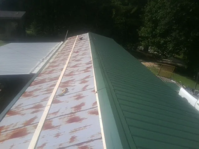 Old rusted panels beside newly installed green metal roofing — Wind Damage Roof Repair by Roofing Brothers in Carmen