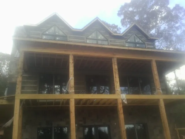 Dormers and porch framing on a large log home under construction — Roof Coating work by our crew in Carmen