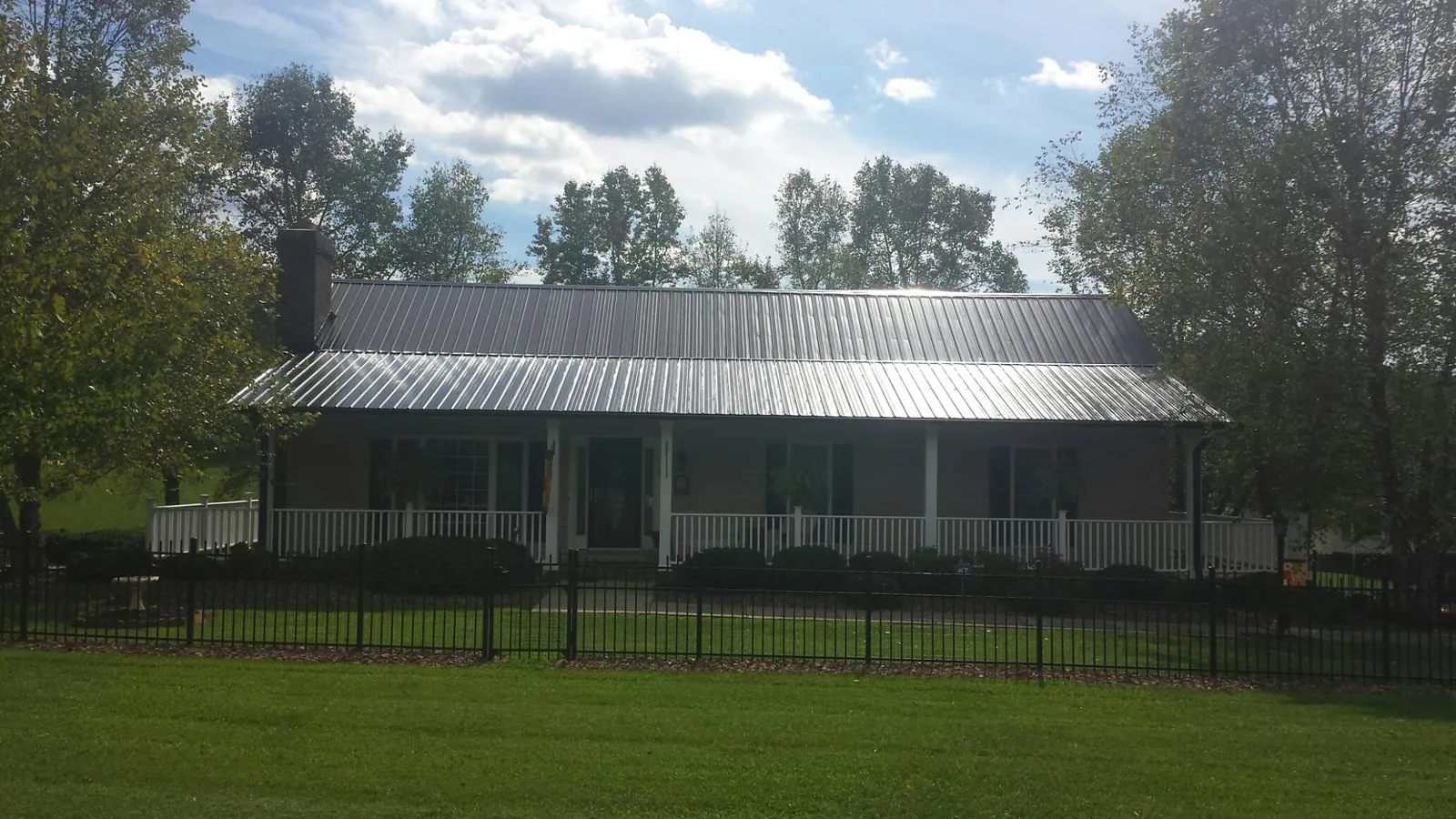 Gray metal roof on a brick ranch with a full width front porch — Gutter Guard Installation work by our crew in Carmen
