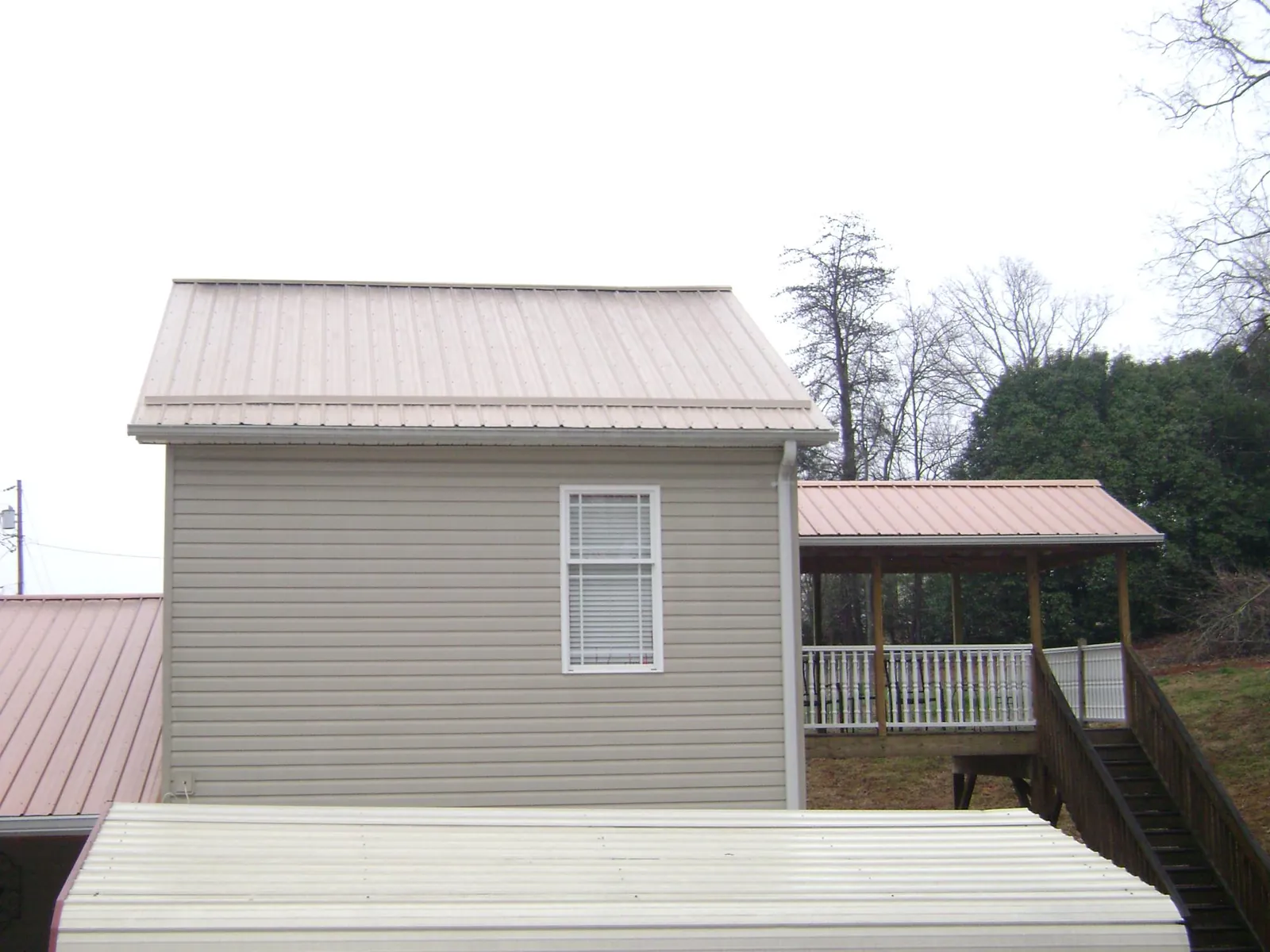 Tan metal roofs on a two story addition and attached porch, from a Roof Replacement job in Carmen