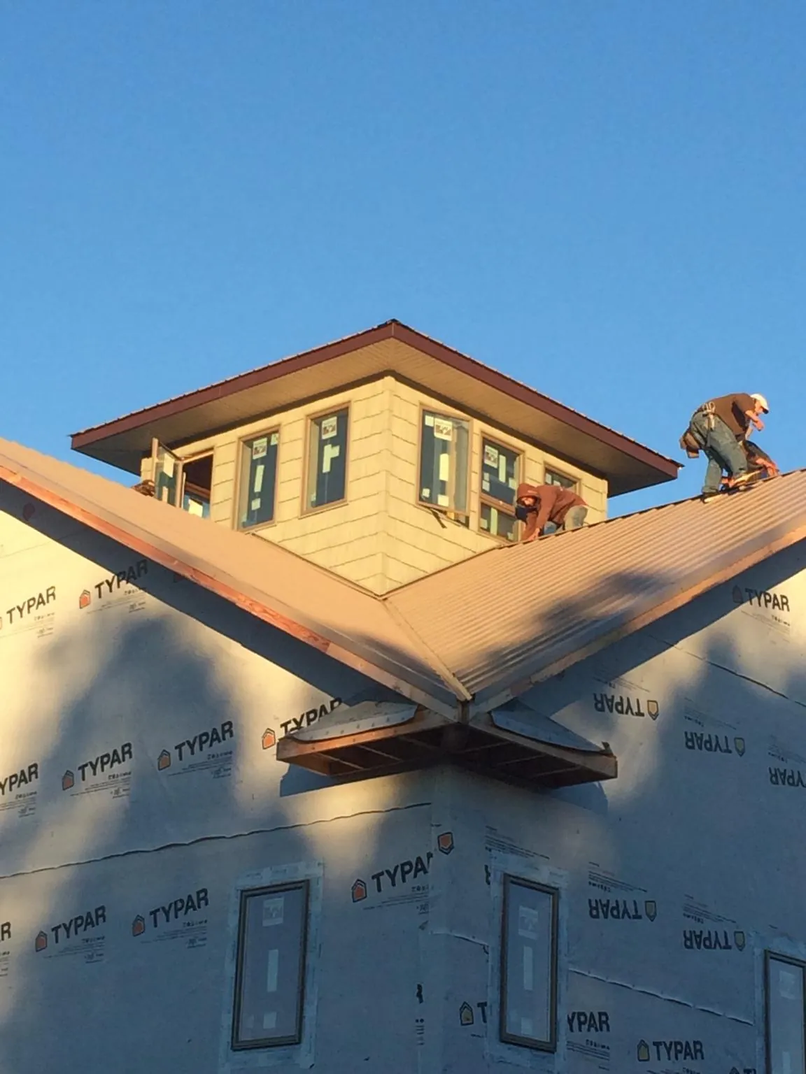 Roofers working around a rooftop cupola on a new metal roof at sunset — Roof Waterproofing in Carmen by Roofing Brothers